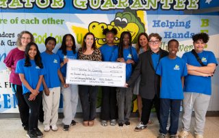 Group shot of Students and staff at Our Lady of Grace holding a big cheque for Nutrition for Learning in hallway
