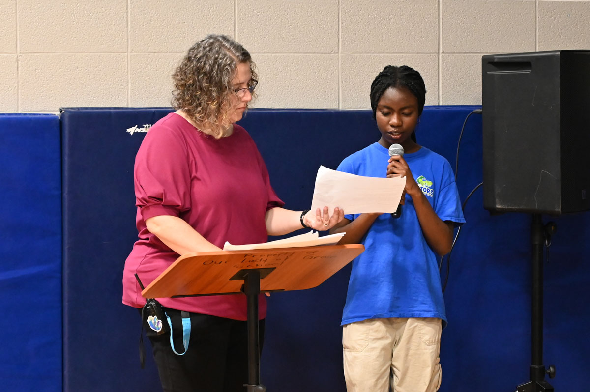 Student speaking into microphone at assembly