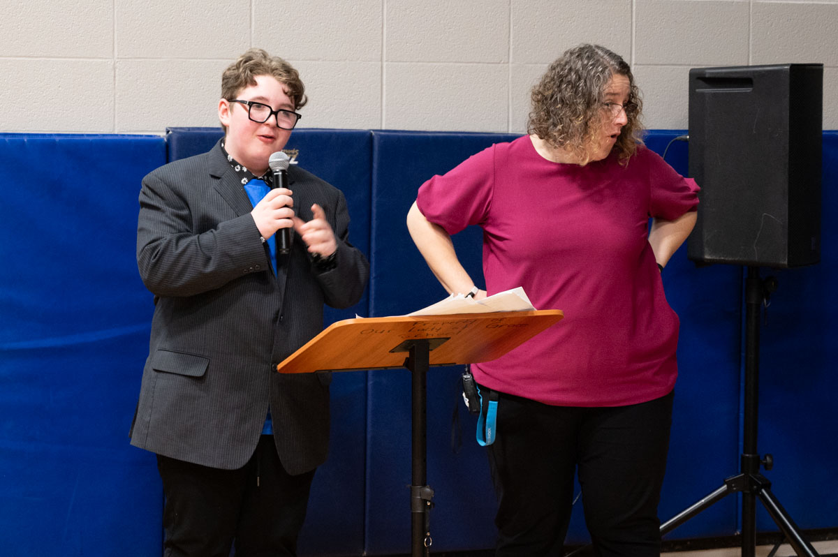 Student talking in a microphone at an assembly