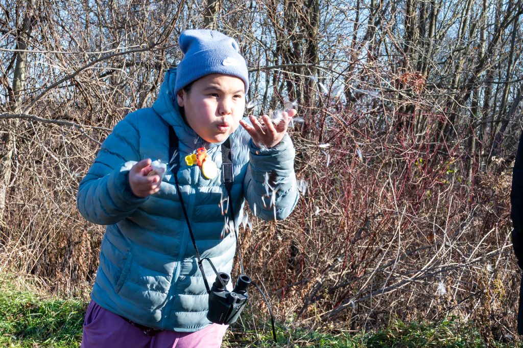 Student blowing milkweed seeds
