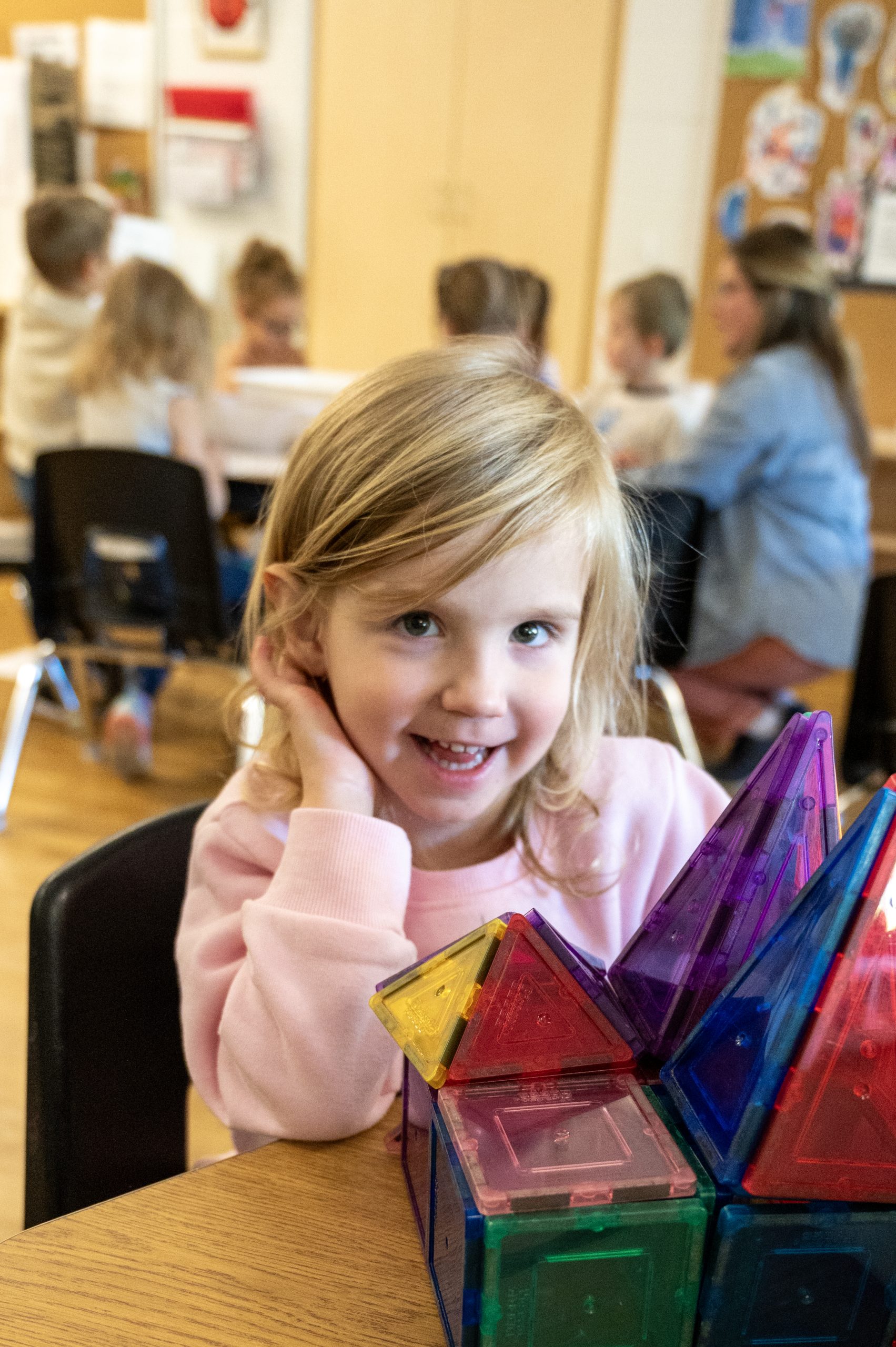 Student posing for photo at her desk while learning with blocks